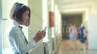 在学校概念上使用智能手机的女学生教育。 年轻的少女和使用生活方式智能手机站在旁边